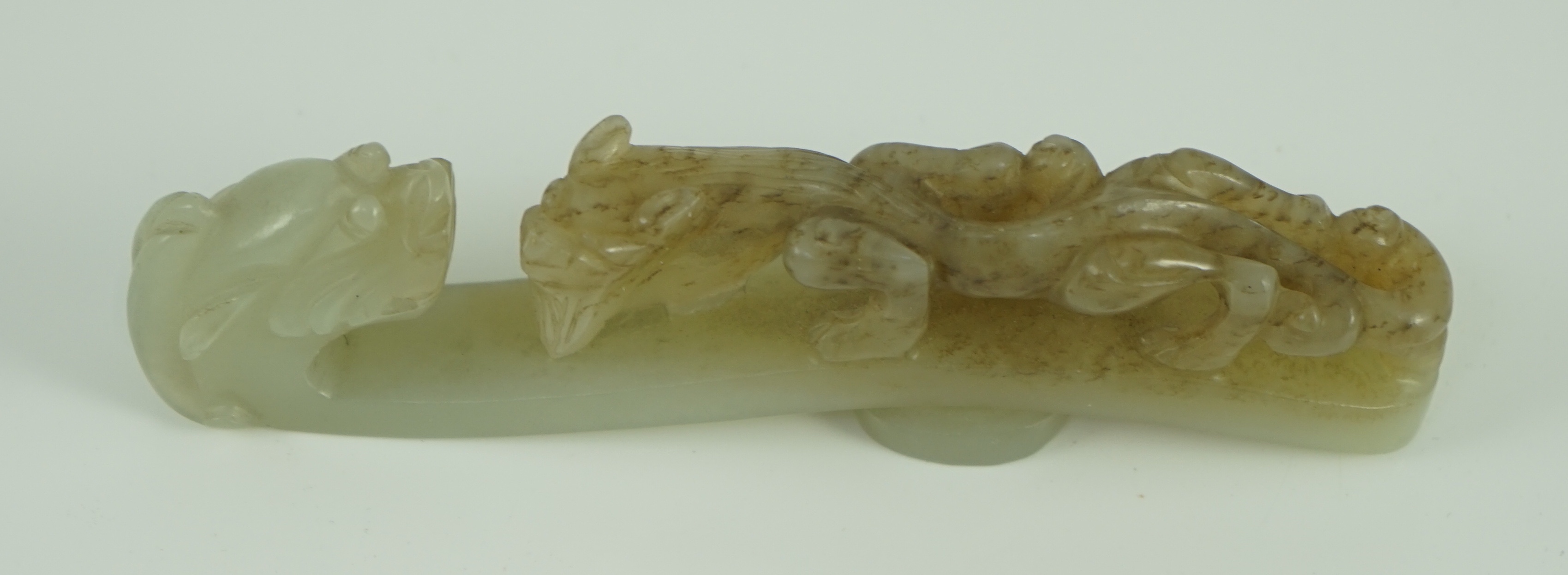 A Chinese pale celadon and brown jade ‘dragon’ belt hook, 18th/19th century 10.7 cm long